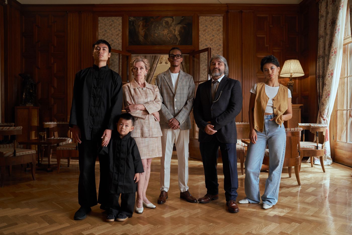 Three generations of one family standing together in a wood-panelled home